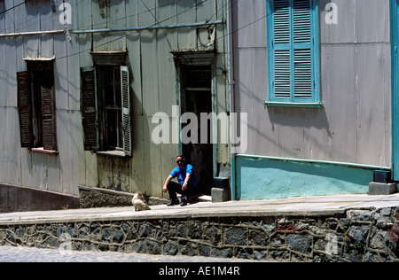 A man sits on the doorstep of his home in Cerro Conception, Valparaiso, Chile, South America. Stock Photo