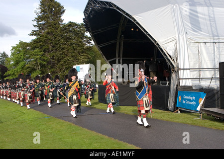 Performance of the Ballater Scottish Pipe marching musicians band with kilts & plaids at Balmoral Castle Musical Evening, Scotland, Aberdeenshire UK Stock Photo