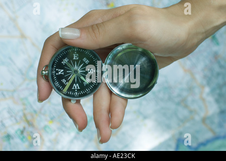 Woman's hand holding compass, map in background Stock Photo