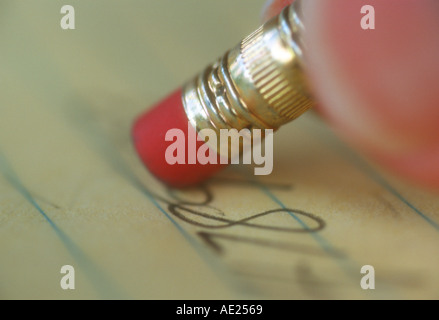 closeup view of fingers using a pencil to erase writing on a legal pad Stock Photo