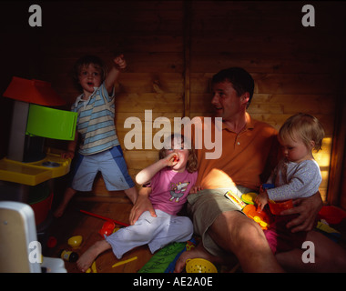 father  and threes kids playing in play house surrounded  by toys and mess Stock Photo