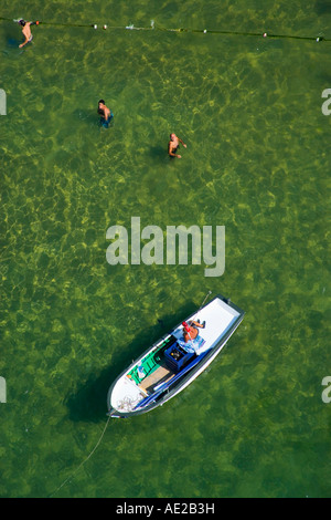 Man sunbathing on a boat and three men swimming in the sea aerial Kilyos Black Sea coast of Istanbul Turkey Stock Photo