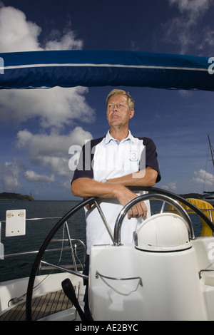 Older man at the helm of a sailing yacht Ile Sainte Pierre off Praslin Seychelles Stock Photo