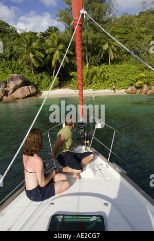 Couple relaxing on bow of a yacht close in to a sandy beach at Anse Lazio Praslin Seychelles Stock Photo