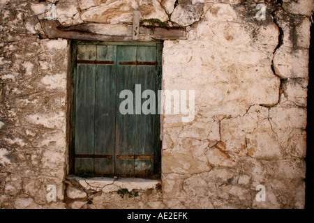 Green shutter over window with cracked stonework Karia Lefkas Greece Stock Photo