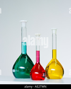 Three flasks of coloured liquid sit on a laboroatory bench Stock Photo