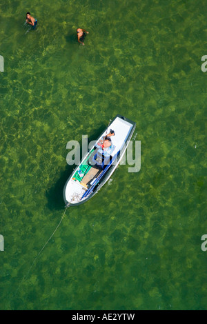 Man sunbathing on a boat and two men swimming in the sea aerial Kilyos Black Sea coast of Istanbul Turkey Stock Photo