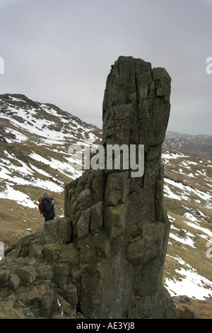 vertical photo of a walker looking up at Eskdale Needle in the Lake District mountains Stock Photo