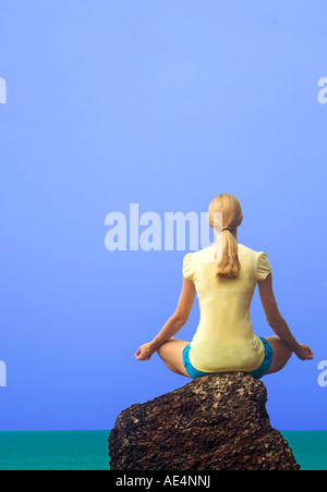 WOMAN PRACTISING YOGA ON ROCK Stock Photo