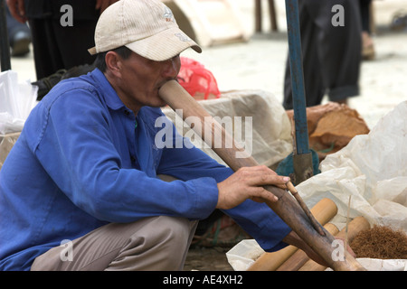 Man tries tobacco in bamboo pipe at Bac Ha hilltribe market known for colourful Flower Hmong traders north Vietnam Stock Photo