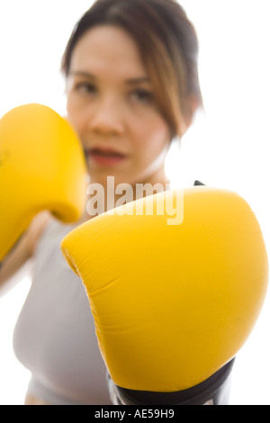 Attractive woman wearing boxing gloves ready to fight with glove in foreground Stock Photo