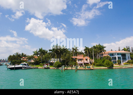 Expensive houses along the waterfront of Palm Island one with a yacht parked in the boat dock Miami Florida Stock Photo