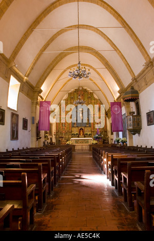 Nave of the Carmel Mission Basilica looking down the aisle of pews to the altar and chancel Stock Photo