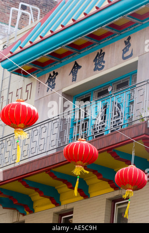Bright red lanterns strung across San Francisco Chinatown street in front of colorful balcony with Chinese characters Stock Photo