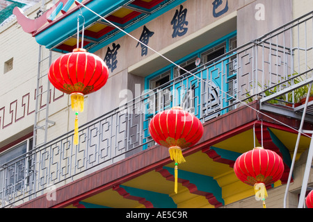 Bright red lanterns strung across San Francisco Chinatown street in front of colorful balcony with Chinese characters Stock Photo