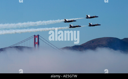 US Navy Blue Angels jet airplanes flying in formation over Golden Gate Bridge in fog in San Francisco California Stock Photo