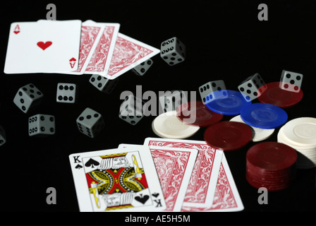 A pair of dice rolling across some poker chips and playing cards in a gambling scene Stock Photo