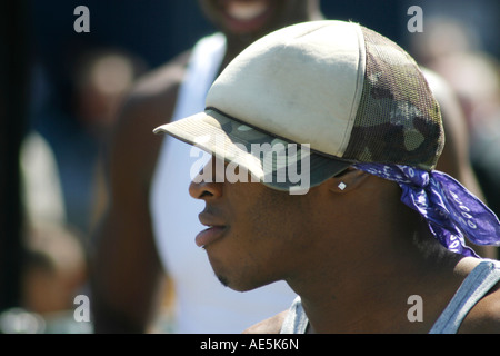 Profile of a young black man with a lip piercing earring camouflage hat and purple bandanna Union Square New York City Stock Photo