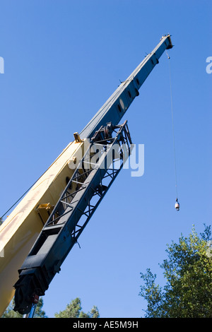 Large crane with hydraulic telescopic arm lowering the hook on a cable from the boom at a construction site Stock Photo