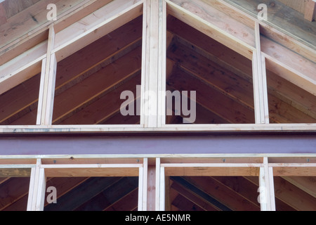 Metal and wood framing of room with cathedral ceilings and wall of windows at residential construction site Stock Photo