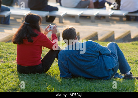 Woman sitting on grass with her husband taking photo with digital camera Stock Photo