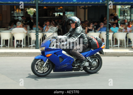 St Tropez waterfront motor bike rider hot summers day driving past pavement bars Stock Photo