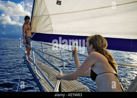 Woman photographing another woman posing on front of yacht Sea Star Sailing Yacht Seychelles Stock Photo
