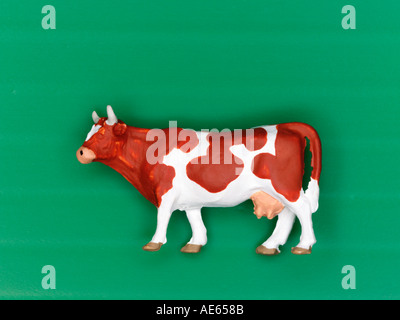 Plastic model cow on green background Stock Photo