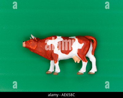 Plastic model cow on green background Stock Photo