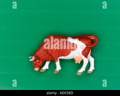 Plastic model cow grazing on a green background Stock Photo