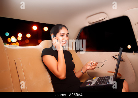 RHS70944 South Asian Indian young executive lady in a Honda car talking on mobile and working on laptop Model Release 522 Stock Photo