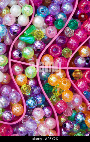 Colourful glass beads in a bright pink curved plastic box Stock Photo