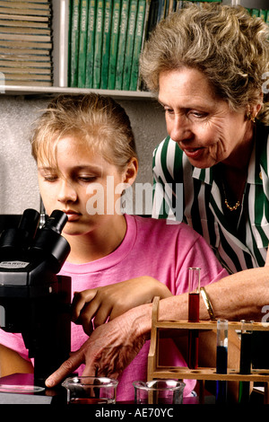 Student age 13 in Eighth grade learning science with teacher helping to learn at desk Stock Photo