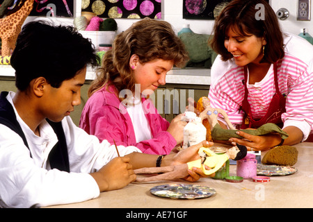 Student girls age 13 in Eighth grade learning art with teacher helping at school Stock Photo