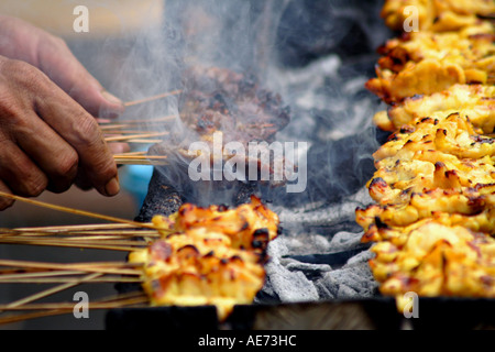 Hands Turning Chicken and Beef Satay on a Grill, Kuching, Sarawak, Borneo, Malaysia Stock Photo
