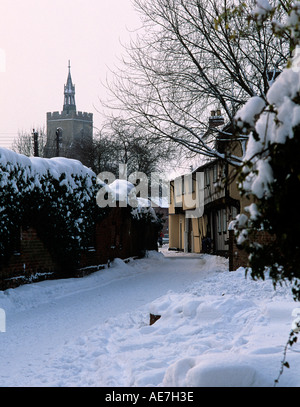 Snow covered village lane with medieval timber frame houses and St Mary s Church Suffolk England Stock Photo