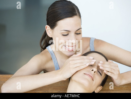 Young woman holding hands over friends eyes from behind Stock Photo