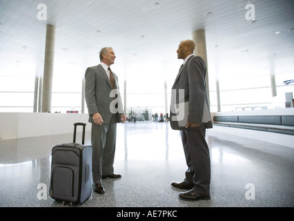 Two businessman standing talking in airport concourse Stock Photo