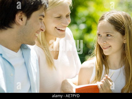 Girl holding book, smiling at parents Stock Photo