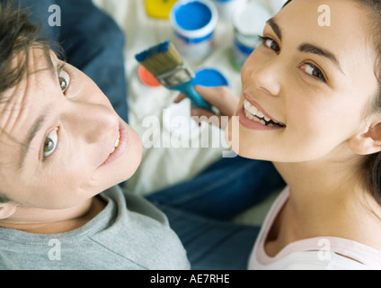 Couple with paint materials, smiling at camera