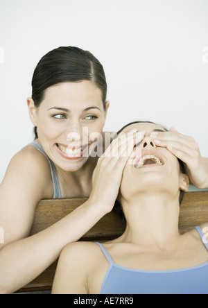 Young woman covering her friend's eyes, both smiling, portrait Stock Photo