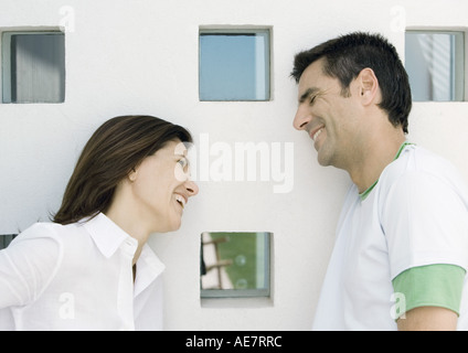 Woman and husband, both leaning against wall with squared windows and smilling Stock Photo