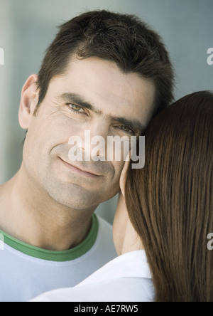 Man resting head against woman's head, smiling, partial view Stock Photo