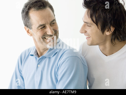 Young man and mature man smiling at each other Stock Photo
