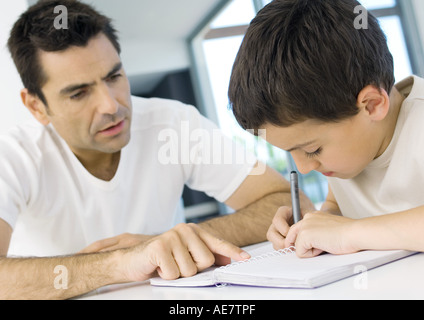Boy doing homework with father's help, cropped Stock Photo