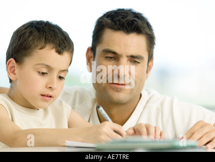 Boy doing homework with father's help, cropped Stock Photo