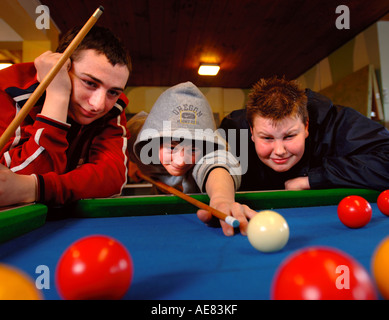 THREE TEENAGE BOYS PLAYING POOL IN A YOUTH CLUB UK Stock Photo