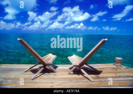 Two wooden deck chairs facing out over the sea towards the horizon in the Caribbean Stock Photo