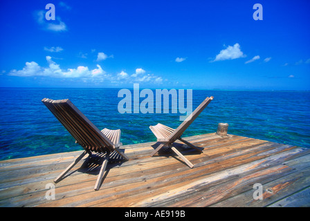 Two wooden deck chairs facing out towards the horizon in the Caribbean Stock Photo