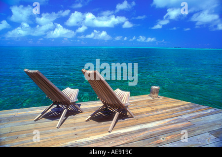 Two wooden deck chairs facing out over sea towards horizon in the Caribbean Stock Photo